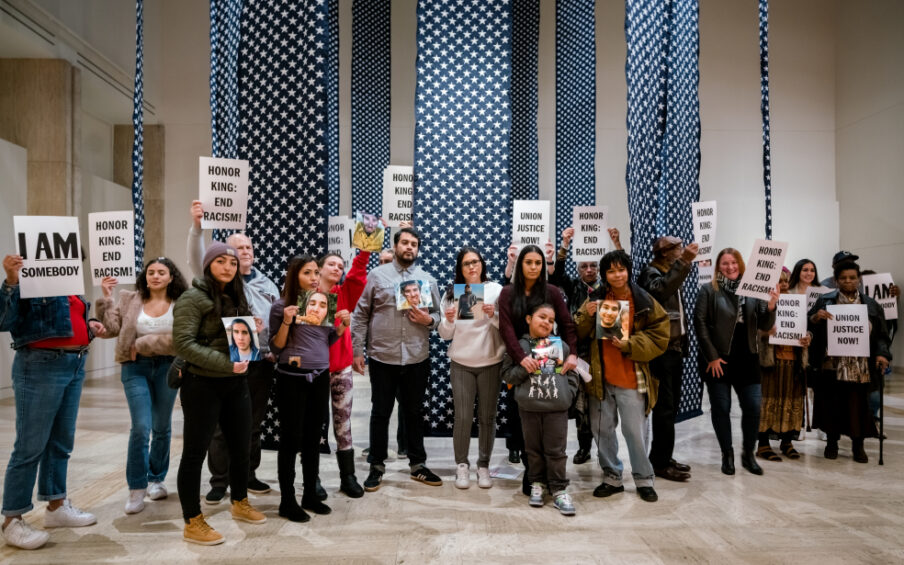 Group of people at the Hank Willis Thomas exhibition holding up signs like "Honor King: End Racism" and "I am Som