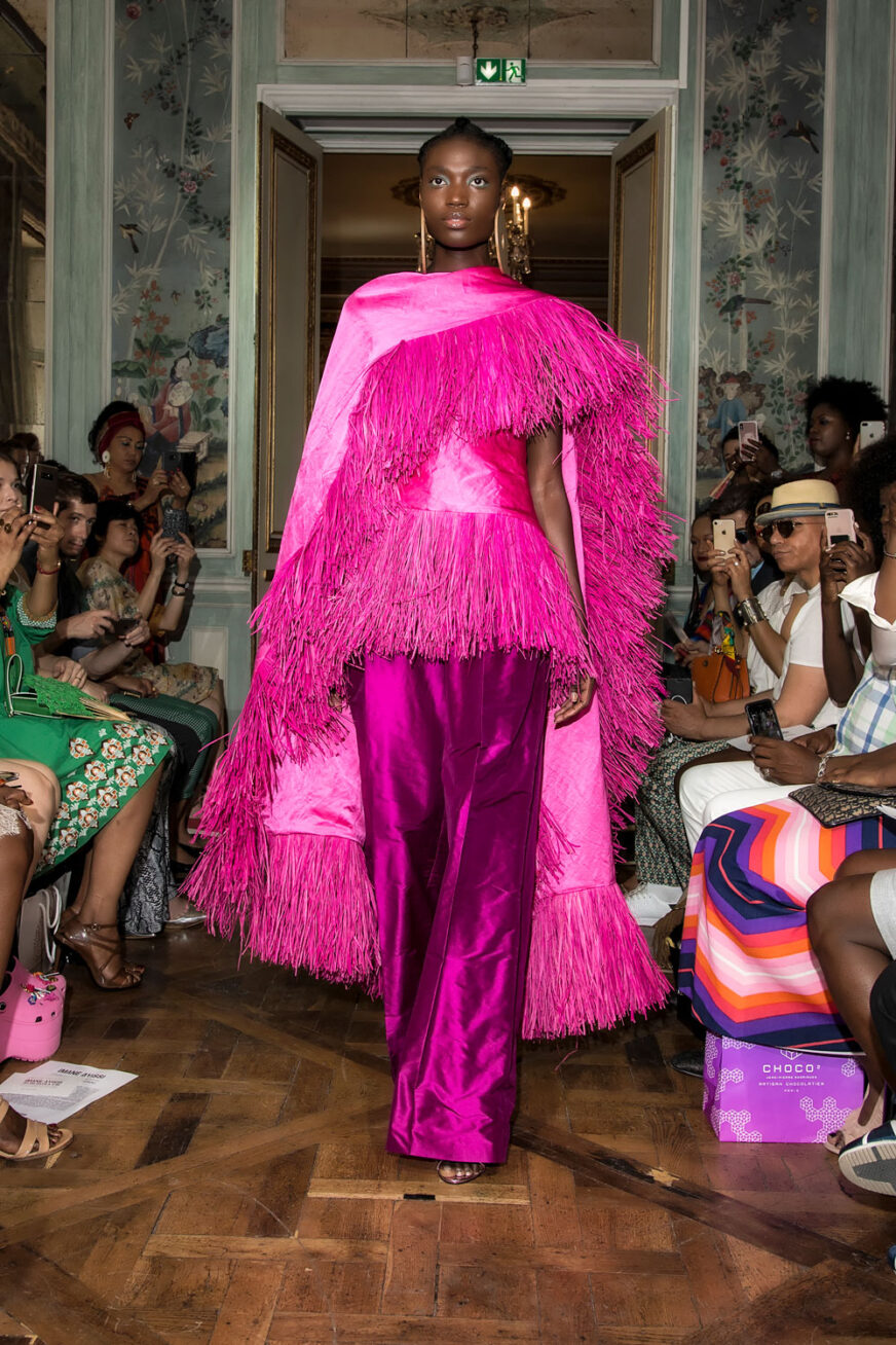 A model on the runway wearing a bright pink outfit.